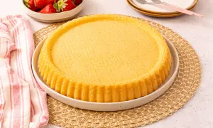 Ein goldbrauner, runder Kuchenboden, perfekt für ein Erdbeerboden Rezept. Daneben eine Schüssel mit frischen Erdbeeren.