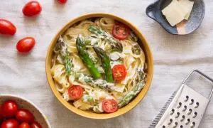 Makaron tagliatelle ze szparagami i pomidorkami koktajlowymi w sosie śmietanowym.