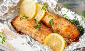 Deux pavés de saumon en papillote, ornés de rondelles de citron et de brins de thym frais, prêts à être dégustés.