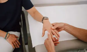 Therapeut untersucht die Hand einer Patientin, um einen Schnappfinger zu behandeln.