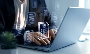 Biznesmen pracuje przy laptopie, przeglądając dokumenty. Wirtualne ikony dokumentów unoszą się wokół, symbolizując zarządzanie danymi. Kto to mocodawca? To ten, kto zleca zadanie.