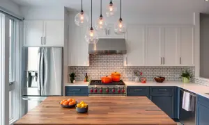 Cucina moderna con isola in legno, elettrodomestici in acciaio e pensili bianchi. Un modo per abbellire una cucina moderna è con tocchi di colore, come le pentole arancioni sul piano cottura.