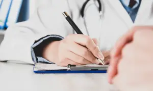 Lekarz pisze na dokumentach, zastanawiając się, czy zwolnienie od psychiatry zostaje w papierach.