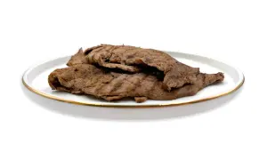 Piatto di paillard di manzo grigliato, sottili fettine di carne con striature scure, servite su un piatto bianco con bordo dorato.