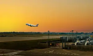 Flugzeug steigt auf vor orangefarbenem Himmel am internationalen Flughafen von London.