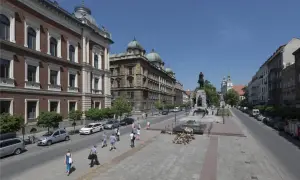 Kraków: pomnik Grunwaldzki, zabytkowe budynki i spacerujący ludzie. Wśród nich można sobie wyobrazić znane osoby z Krakowa.