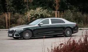 Elegancki Mercedes-Maybach S680 w ciemnozielonym kolorze z dwukolorowym nadwoziem, zaparkowany na tle zieleni.