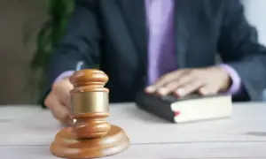 Sędzia kładzie rękę na księdze, obok młotka. Czy adwokat niewykonujący zawodu może chodzić do sądu?
