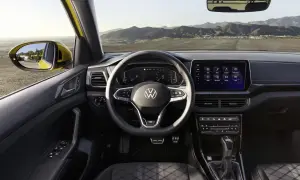 Interni di un'auto Volkswagen con volante, cruscotto digitale e schermo touchscreen. Vista dal posto di guida verso l'esterno.