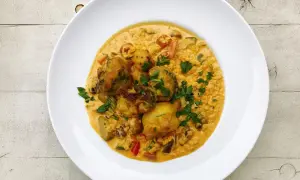 Pyszny ryż z curry z warzywami i kawałkami kurczaka, posypany świeżą natką pietruszki.