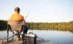 Mężczyzna łowi ryby na spokojnym jeziorze. Zastanawiasz się, ile kosztuje karta wędkarska dla 13 latka?