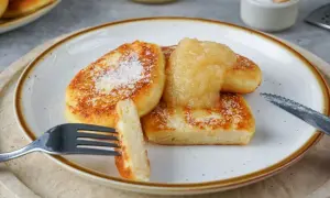 Leckere Quarkkeulchen, goldbraun gebraten und mit Apfelmus und Puderzucker bestreut. Ein perfektes Quarkkeulchen Rezept für Genießer.