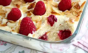 Un délicieux tiramisu framboise, garni de fruits rouges frais et d'amandes effilées, prêt à être dégusté.