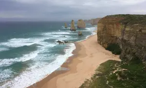 Piękne klify i plaża nad oceanem, kiedy w Australii jest lato. Woda jest turkusowa, a fale rozbijają się o brzeg.