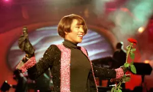 Whitney Houston w Polsce, z mikrofonem i czerwoną różą, w błyszczącej marynarce.