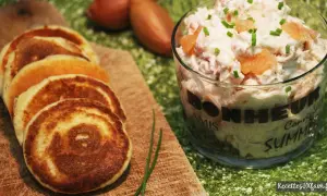 Petits blinis dorés accompagnant un délicieux verre de rillettes de saumon, parsemé de ciboulette fraîche.