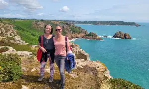 Zwei Frauen genießen den Ausblick auf die Kanalinseln. Tolle kanalinseln urlaub erfahrungen mit türkisfarbenem Meer und Felsen.