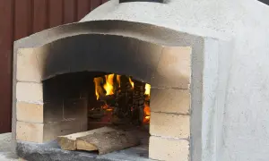En nybyggd kamin murad med tegel och puts, redo för eldning. Värmen sprider sig från den sprakande elden inuti.