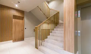 Drewniane lamele i beton architektoniczny to świetne pomysły, co położyć na ściany na klatce schodowej. Nowoczesna klatka schodowa z windą.
