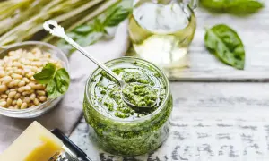 Pesto di basilico senza aglio in un barattolo, con pinoli, parmigiano e olio d'oliva. Ingredienti freschi per un sapore delicato.