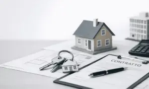 Chiavi con portachiavi a forma di casa, contratto, calcolatrice e modelli di edifici. Potrebbe essere una **monitoria di sgombero** o un accordo immobiliare.