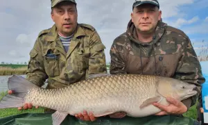 Dwóch wędkarzy prezentuje imponującego karpia o wadze 22 kg, złowionego na łowisku Nowe Żukowo.