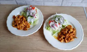 Dwa talerze z kurczakiem w przyprawach i sałatką z pomidorów, ogórków i cebuli. Tak wygląda pyszna shoarma co to za danie!