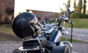 Czarny kask motocyklowy z napisem "Scorpion" i grafiką skorpiona, oparty o siedzenie choppera.