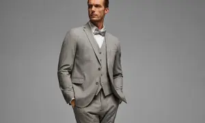 Ein Mann im eleganten grauen Anzug mit Weste und Fliege. So gelingt das Anzug reinigen ohne waschen.