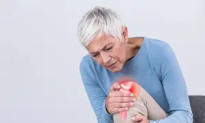 Frau mit Arthrose-Schmerzen im Knie, die sich fragt, welche Vitamine bei Arthrose helfen könnten.