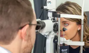 Un ophtalmologue examine l'œil d'une patiente avec un biomicroscope.