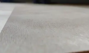 Textura de madera de okume arbol, con vetas finas y claras, mostrando la belleza natural del material.