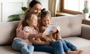 Mama czyta swoim córeczkom krótkie wierszyki dla bff. Radość i bliskość na kanapie.