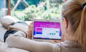 Kobieta przegląda w aplikacji Wizz Air na tablecie, planując tani lot.