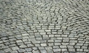 Szara kostka granitowa ułożona łukiem. Dokładne ile kostki granitowej na m2 zależy od jej wymiarów.