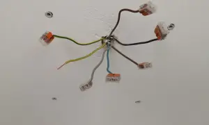 Sufit z instalacją elektryczną. Widać kilka przewodów, w tym czarny kabel elektryczny, połączonych złączkami.