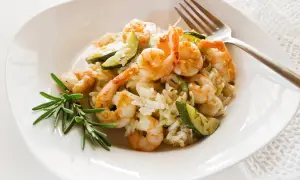 Cremiges Risotto mit Garnelen und Zucchini, garniert mit Rosmarin. Ein köstliches Gericht, das Lust auf mehr macht.