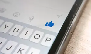 Kciuk w górę na ekranie telefonu, pokazujący, jak działa aktywność na Messengerze. Klawiatura i ikony czatu.