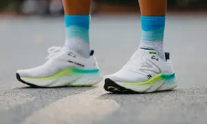 Białe buty do biegania New Balance z kolorową podeszwą i skarpetki w chmurki. Dowiedz się, jak dobrać buty do biegania.