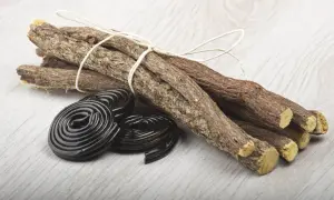 Korzenie lukrecji związane sznurkiem i czarne, spiralne cukierki. Idealne do przygotowania naparu z lukrecji.