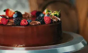 Una deliziosa torta di compleanno con frutta e cioccolato, decorata con fragole, lamponi, mirtilli e more.