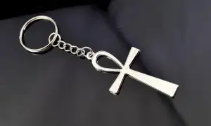 Srebrny brelok z symbolem ankh, starożytnym egipskim znakiem życia, na czarnym tle.