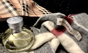 Flakon perfum Burberry Weekend obok szarego szala z charakterystyczną kratą. Idealny zestaw na weekend.