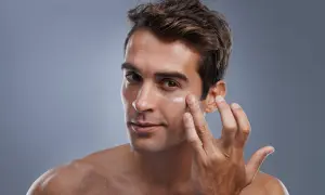 Hombre aplicándose crema en el rostro. El cuidado facial del hombre es esencial para una piel sana y radiante.