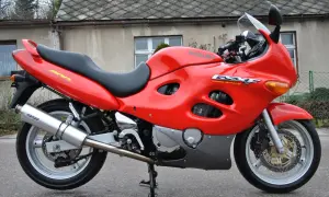 Czerwony motocykl Suzuki GSX-F 600 z czarnym siedzeniem, zaparkowany przed budynkiem.