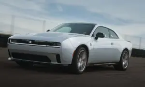 Biały Dodge Challenger Hellcat pędzi po torze wyścigowym, jego sylwetka jest dynamiczna i agresywna.