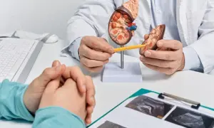 Lekarz wyjaśnia pacjentowi, jak wygląda biopsja nerki, używając modelu narządu. Na stole leżą wyniki badań USG.