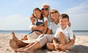 Famiglia felice in spiaggia, i nonni si godono il sole mentre i figli sono in vacanza con loro.