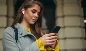 Kobieta w słuchawkach bezprzewodowych korzysta z telefonu.