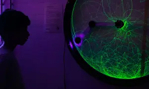 Ein Junge bestaunt ein Doppelpendel mit grünen Lichtspuren bei der Nacht der Wissenschaft Berlin.